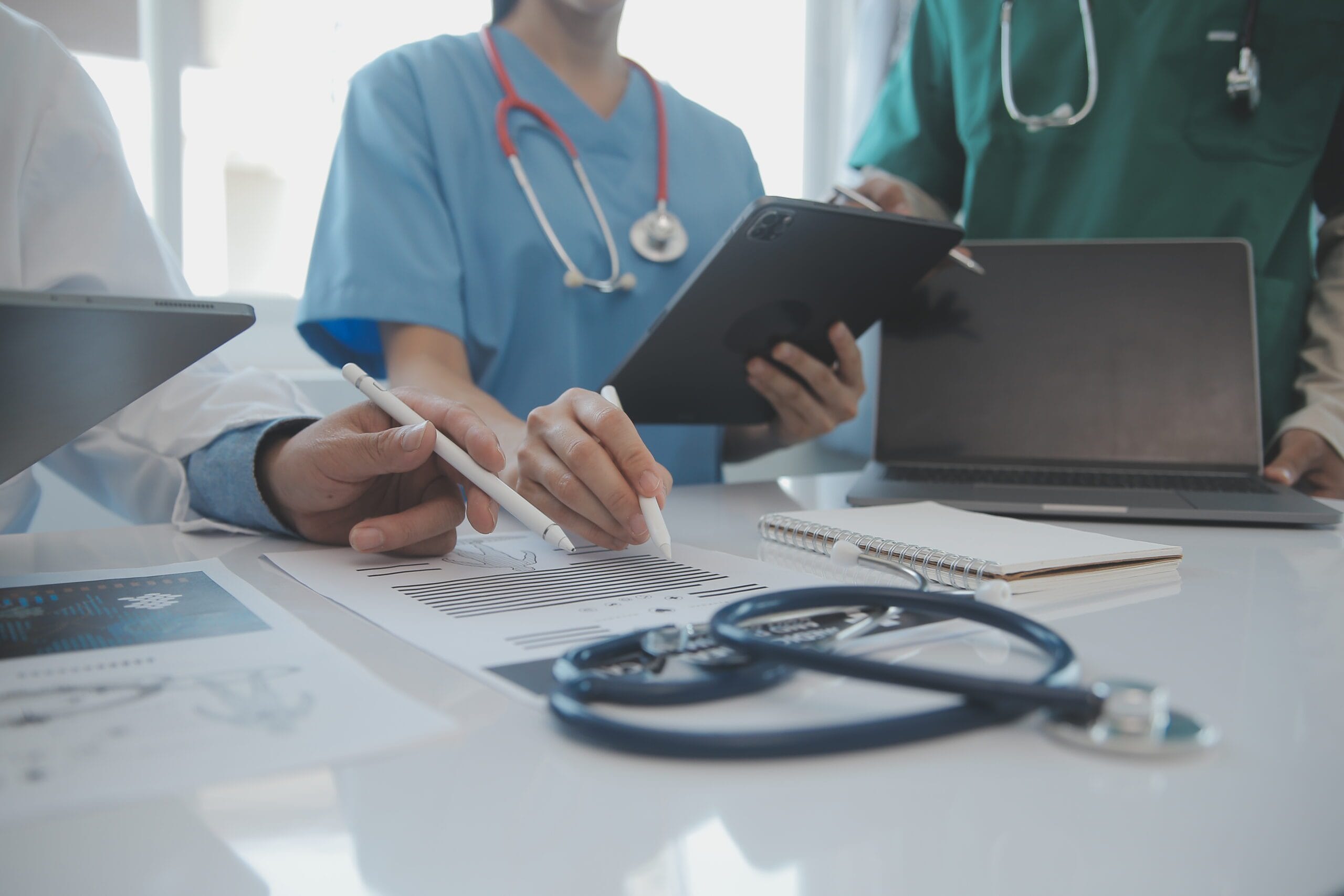 A medical scribe documenting patient information while a physician interacts with a patient.