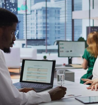 Healthcare professional discussing patient data with a colleague in a modern office environment.