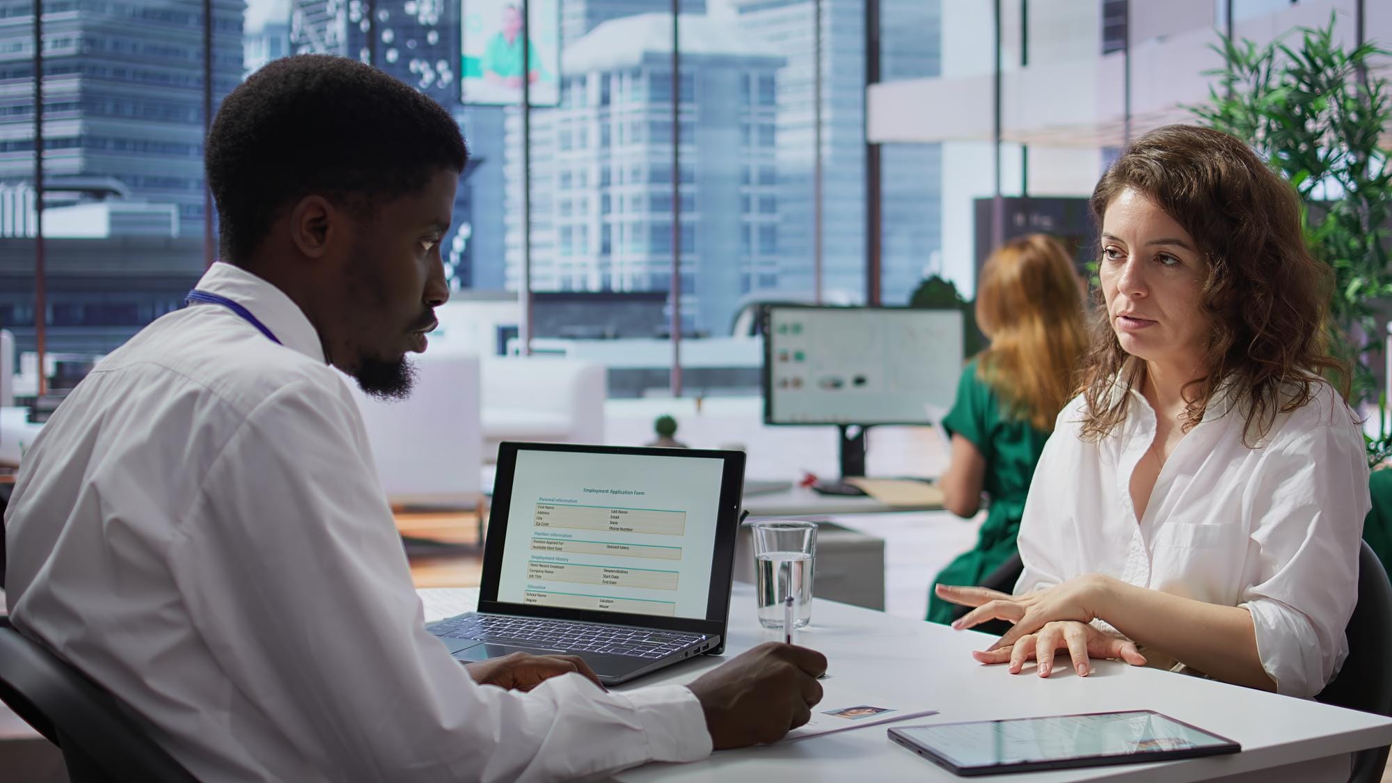 Healthcare professional discussing patient data with a colleague in a modern office environment.