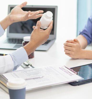 A healthcare administrator reviewing prior authorization requirements on a computer.