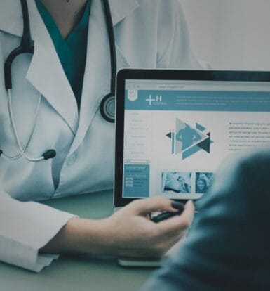 Doctor explaining healthcare services on a laptop to a patient.