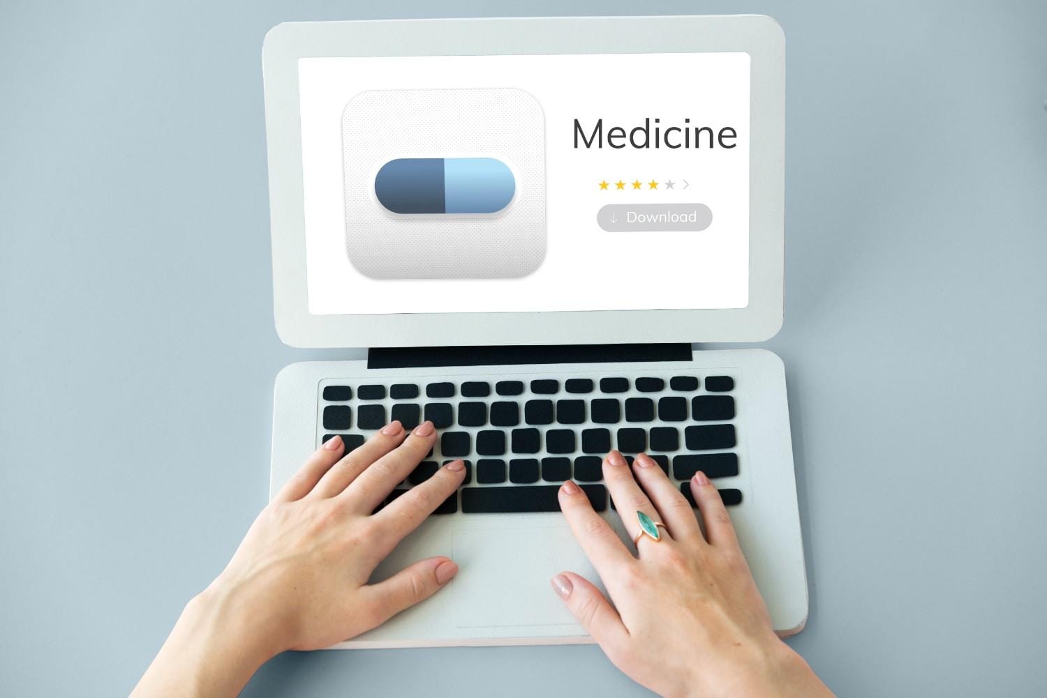 Hands typing on a laptop displaying a medicine review with star ratings and a download button, symbolizing online reviews in healthcare.