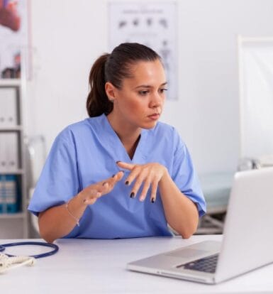 A virtual healthcare assistant in scrubs working on a laptop to improve medical billing and patient data management.