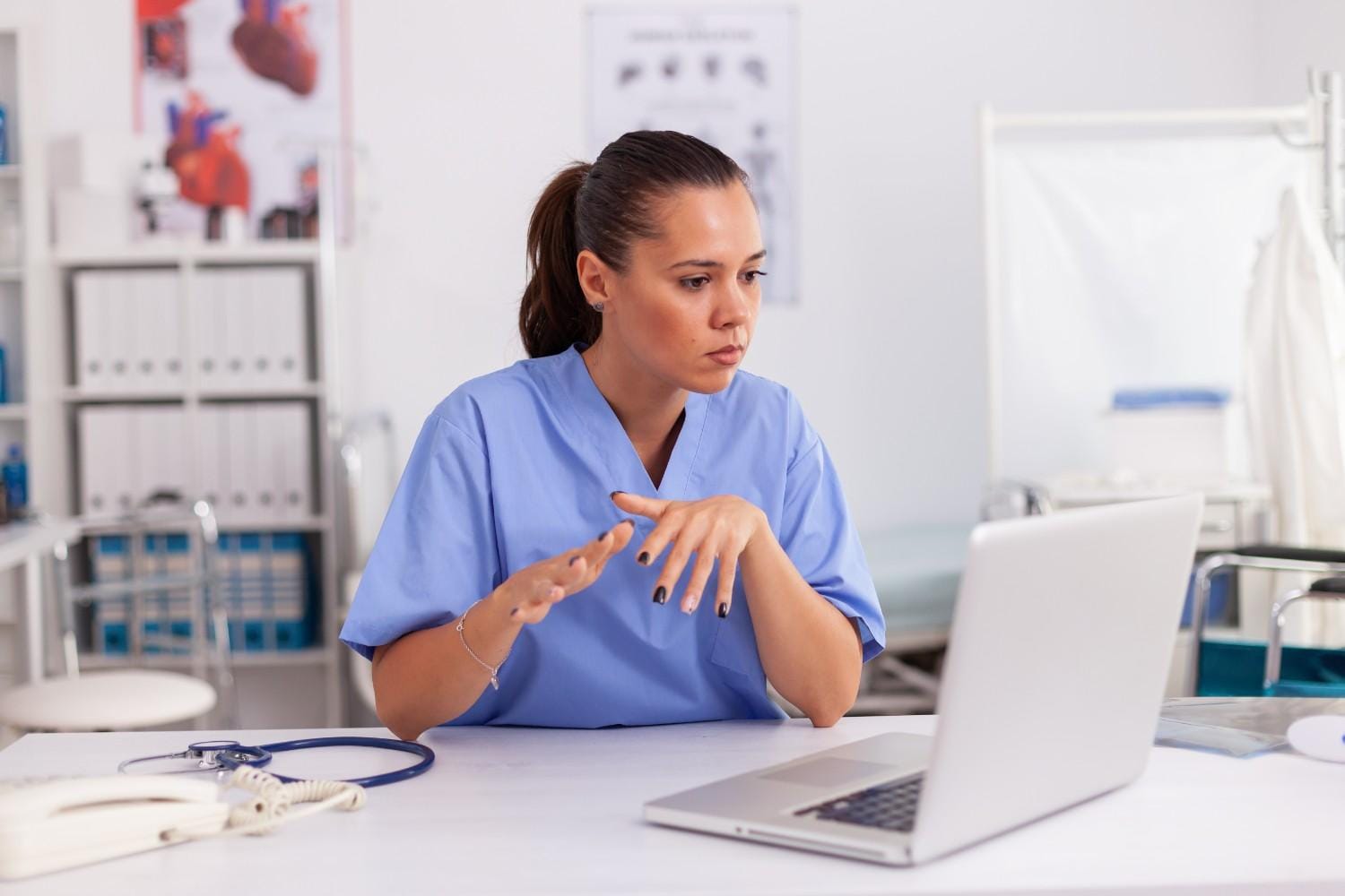 A virtual healthcare assistant in scrubs working on a laptop to improve medical billing and patient data management.