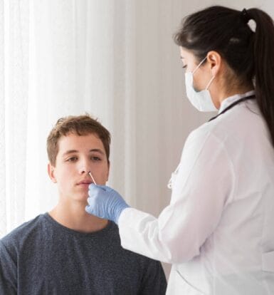 Doctor performing a nasal swab test on a young patient during a clinical visit, representing the careful documentation required in medical processes like prior authorization.