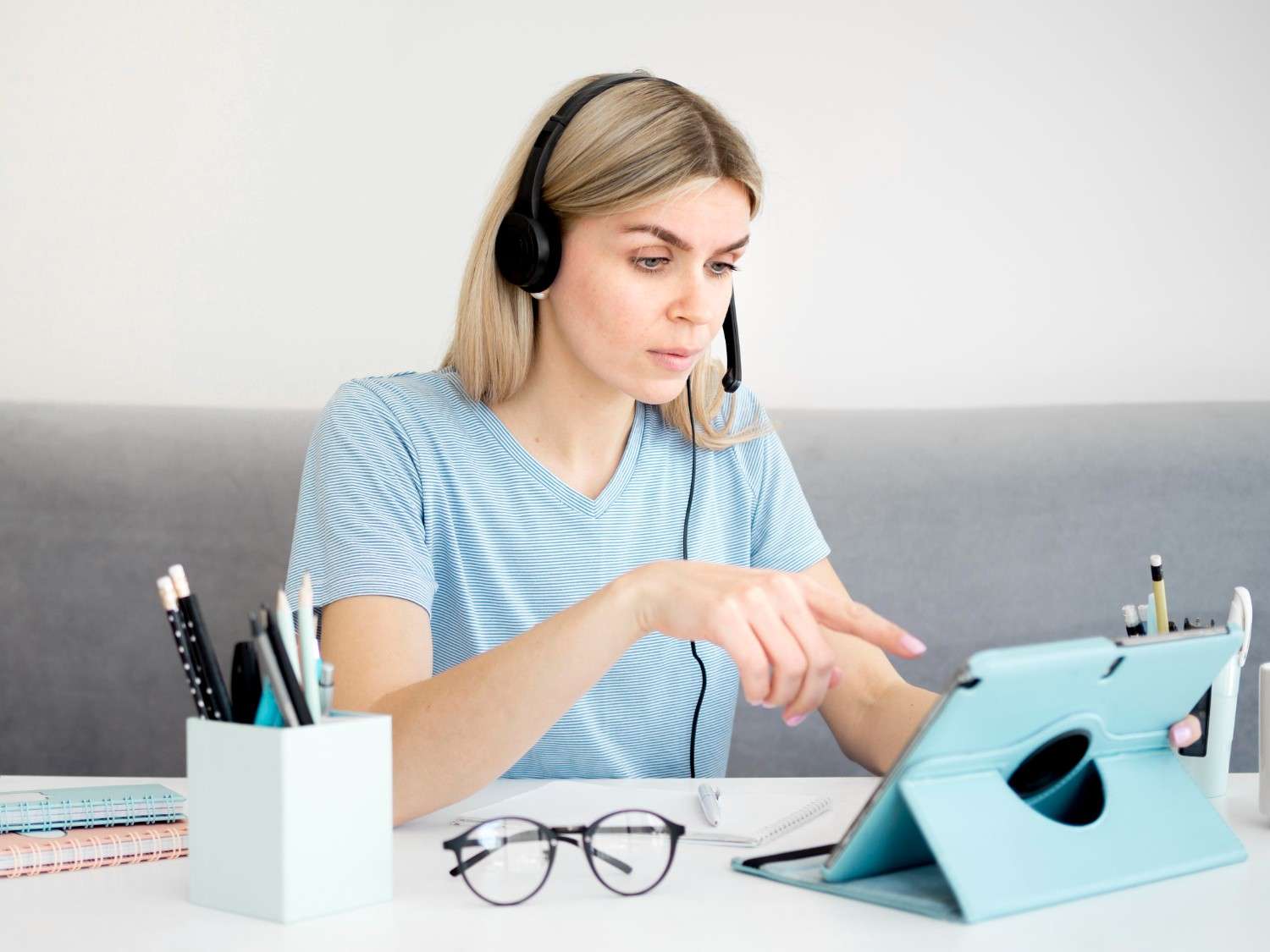 A virtual medical assistant wearing a headset, working on a tablet while managing healthcare tasks remotely.