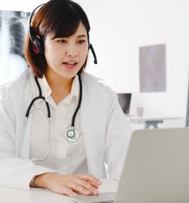 Doctor using a virtual assistant on a laptop to manage administrative tasks remotely in a medical practice.