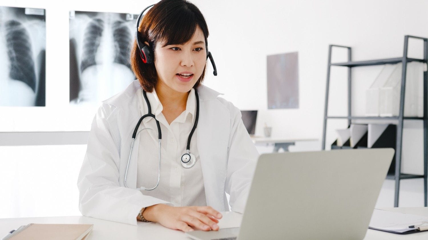 Doctor using a virtual assistant on a laptop to manage administrative tasks remotely in a medical practice.