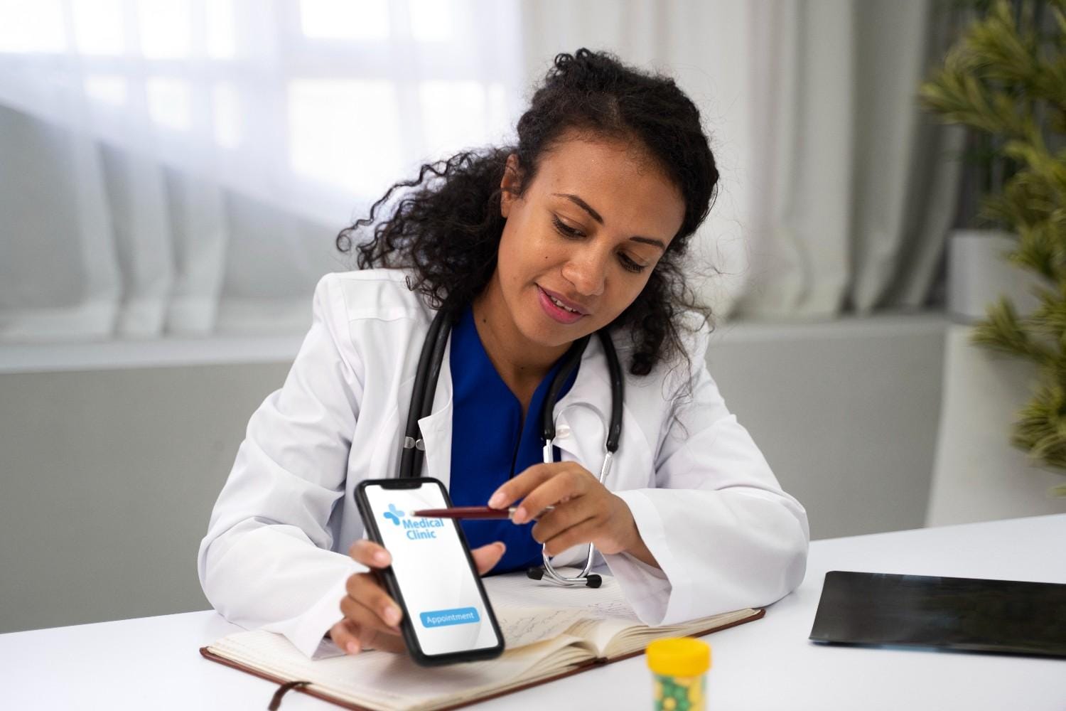 A female doctor using a mobile app for medical clinic appointment scheduling while reviewing notes in her office.