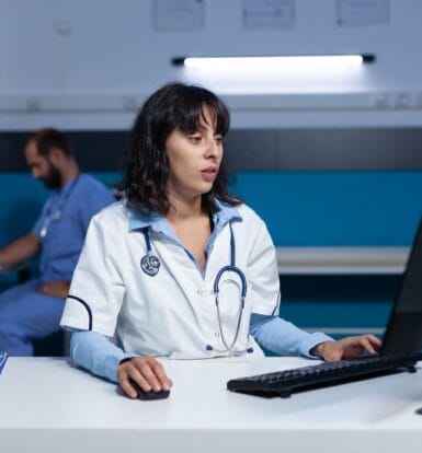 A healthcare professional using a computer for EMR management in a clinical setting.