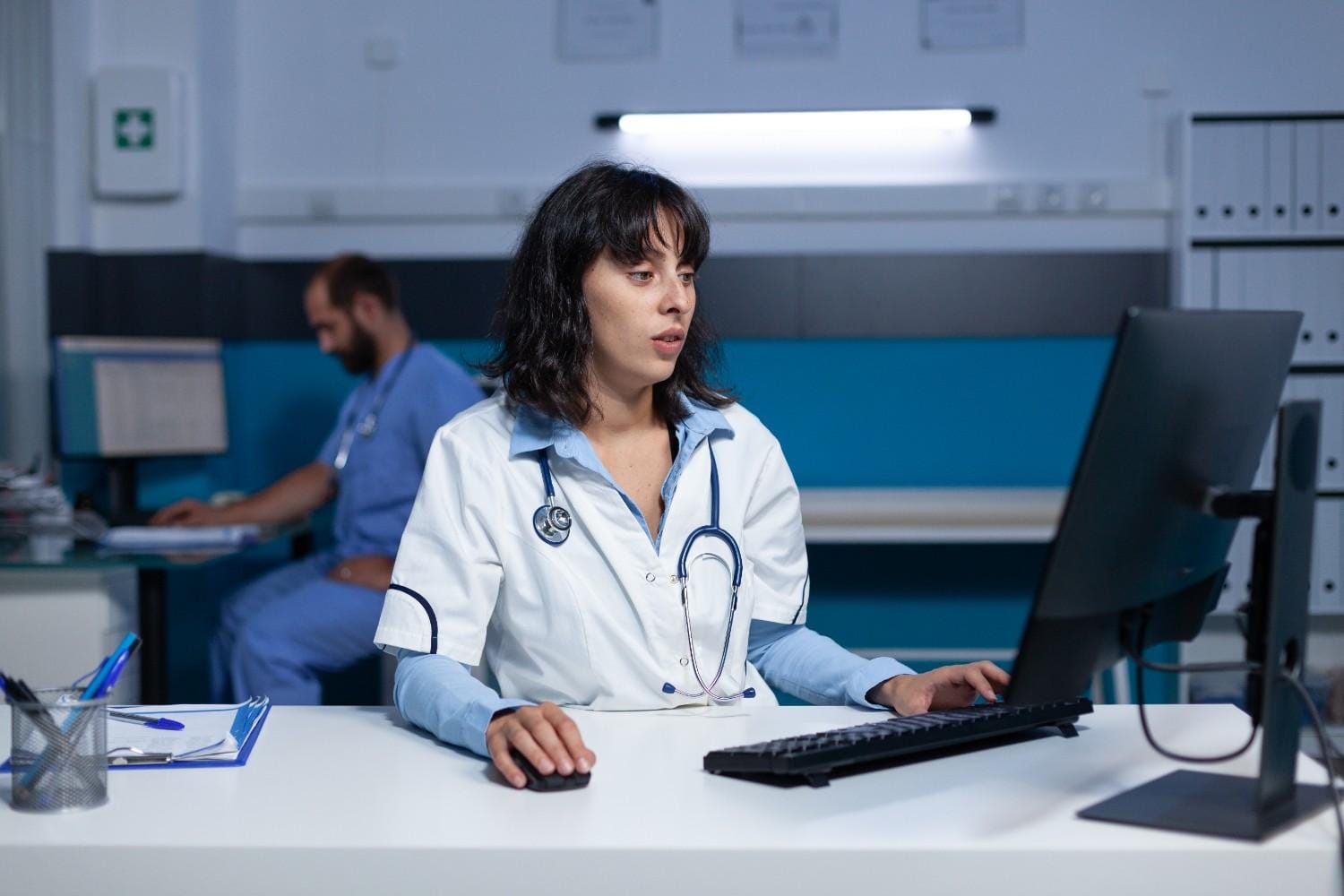 A healthcare professional using a computer for EMR management in a clinical setting.