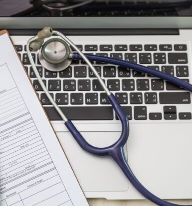 Medical history form and stethoscope on a laptop keyboard