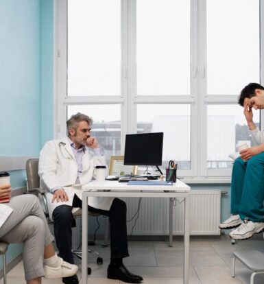 A group of stressed healthcare professionals sitting in a medical office, reflecting the challenges faced in the healthcare industry, such as staffing shortages and administrative overload.