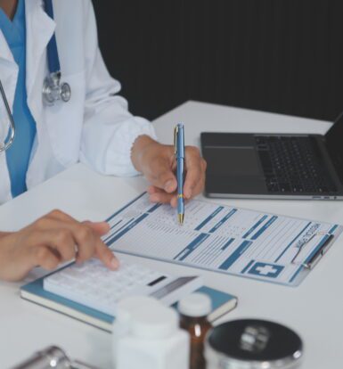 Healthcare professional using a computer to verify patient insurance eligibility, streamlining the prior authorization process with technology.