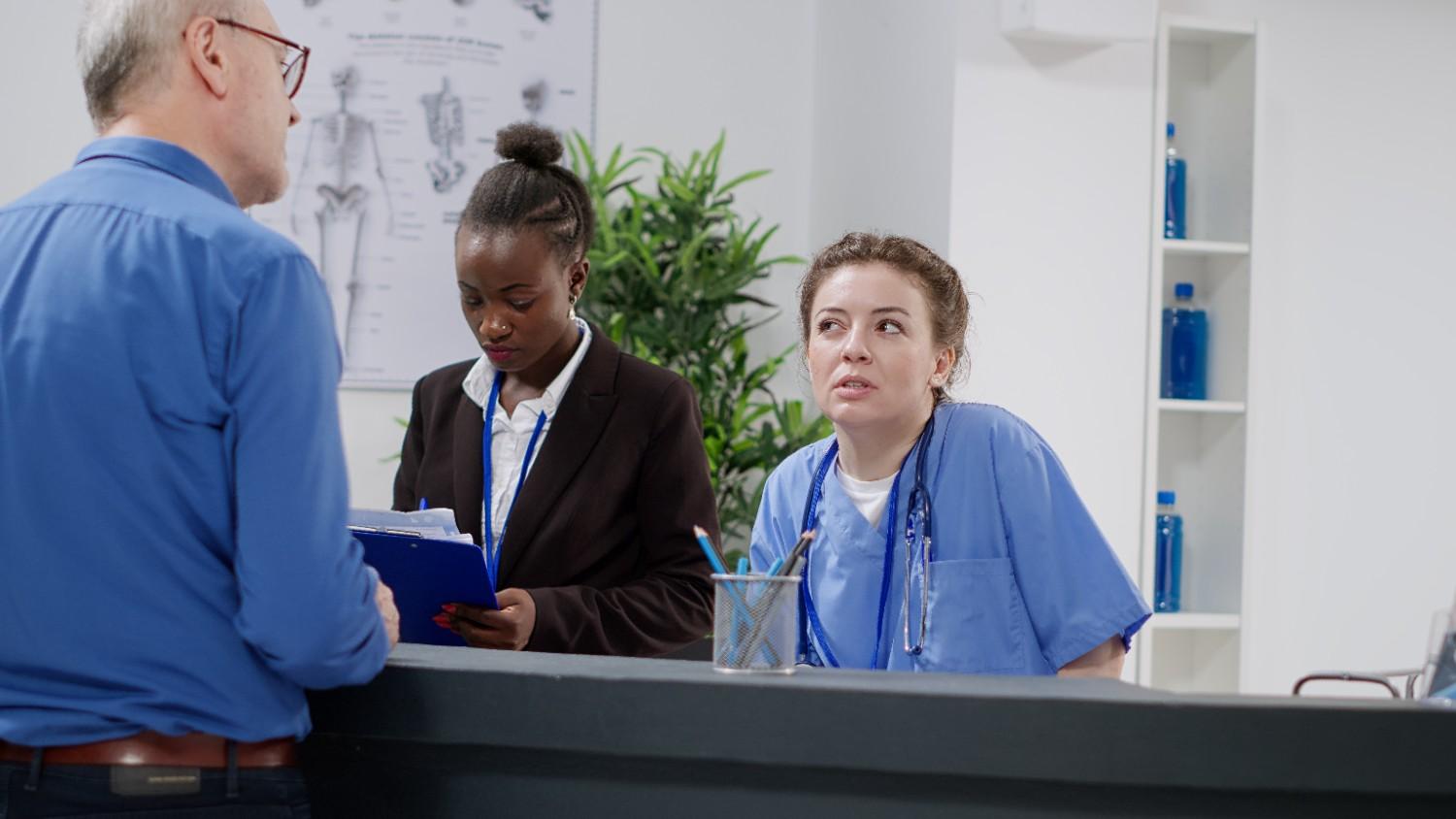 Medical Receptionists Assisting a Patient at a Healthcare Front Desk in Rhode Island