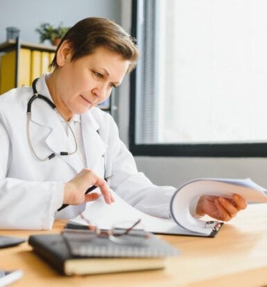 A doctor reviewing paperwork for prior authorizations in Florida, highlighting administrative challenges in healthcare.