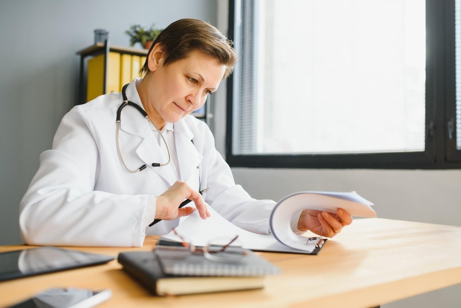 A doctor reviewing paperwork for prior authorizations in Florida, highlighting administrative challenges in healthcare.