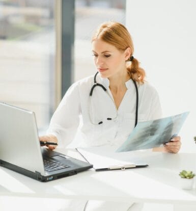 Medical coder reviewing patient charts on a computer in a Florida clinic.