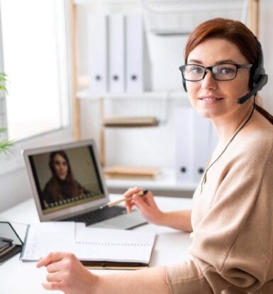 Virtual assistant working remotely, wearing a headset, assisting with healthcare administrative tasks through a video call.