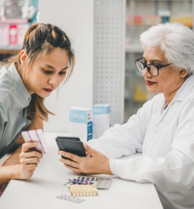 A pharmacist assisting a customer with prescription billing and payment options at a long-term care pharmacy.