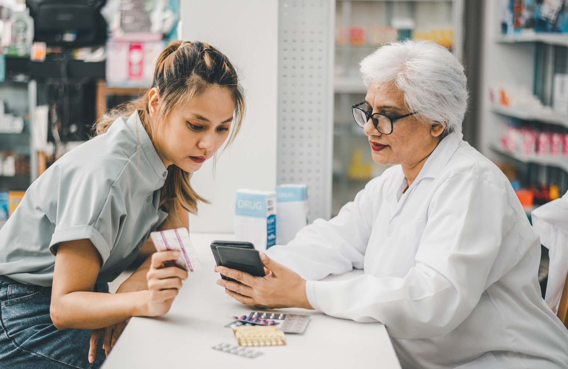 A pharmacist assisting a customer with prescription billing and payment options at a long-term care pharmacy.