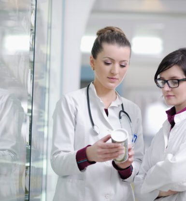 Two pharmacists reviewing a medication bottle in a pharmacy.