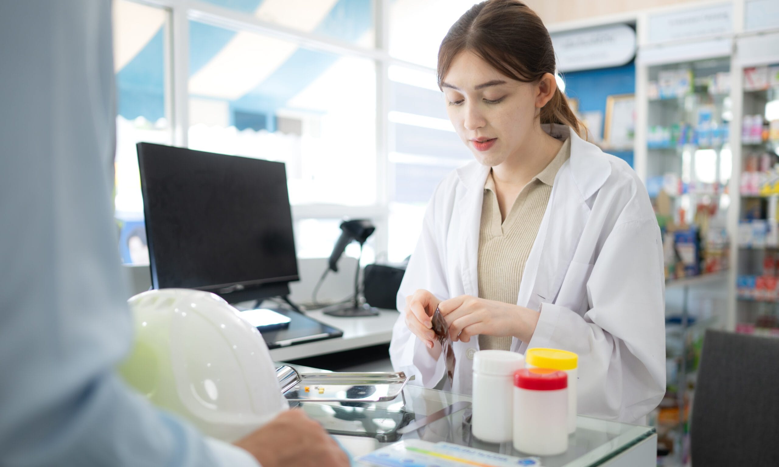 A smiling pharmacy professional working on billing, showcasing cost savings.