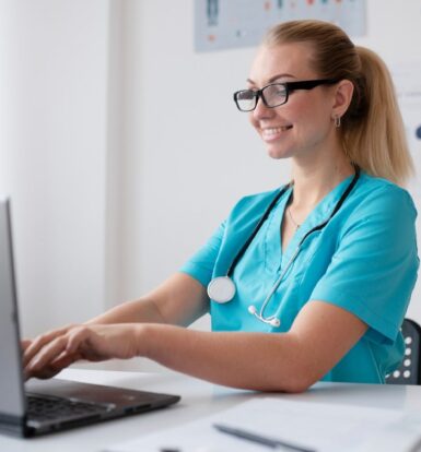 Smiling virtual medical assistant in scrubs using a laptop to provide administrative support for healthcare providers in New Jersey.