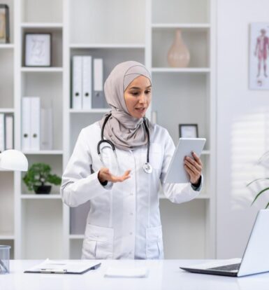 Female doctor in a modern medical office using a tablet for virtual patient consultation.