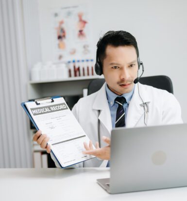 A medical coder working on a computer with a HIPAA compliance checklist on the screen.