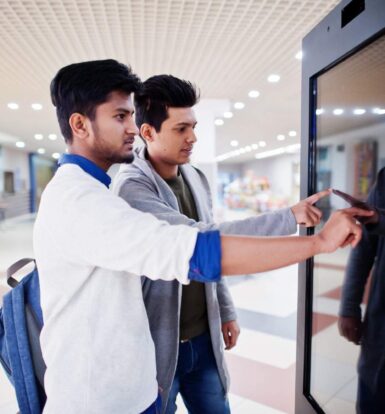 Two people interacting with a touchscreen digital kiosk, representing automated solutions in healthcare for appointment scheduling