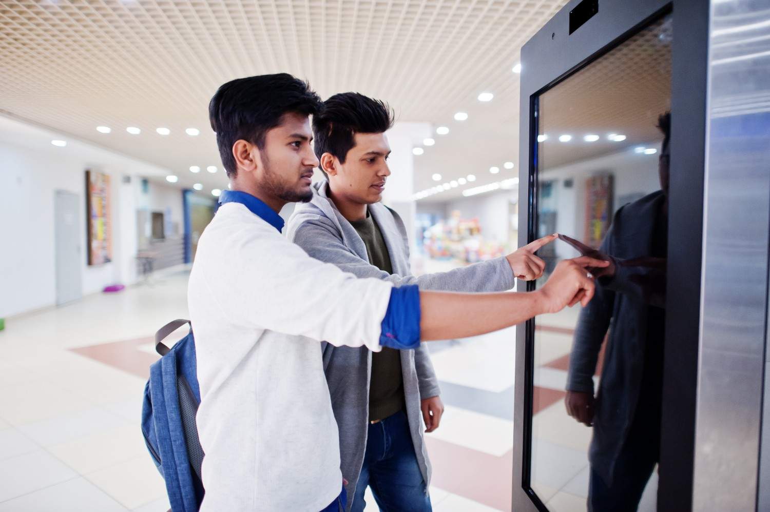 Two people interacting with a touchscreen digital kiosk, representing automated solutions in healthcare for appointment scheduling