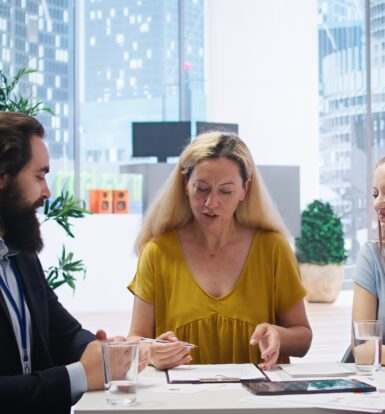 A healthcare team of three professionals collaborating on strategies to improve prior authorization processes in a modern office setting.