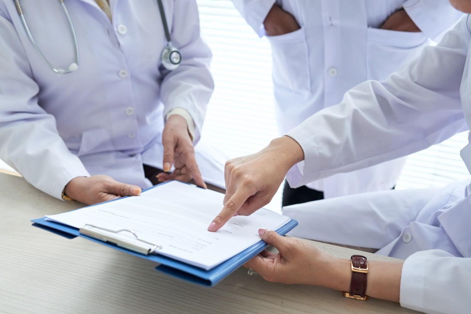 Doctors reviewing prior authorization documents in a hospital setting - Prior Authorization Outsourcing for Hospitals