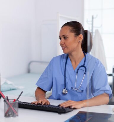 Virtual Medical Assistant working at a desk in a healthcare setting, managing administrative tasks with a computer.