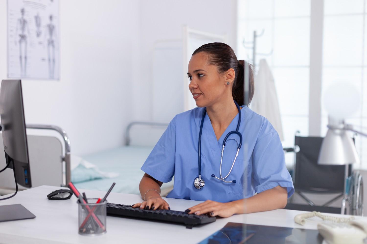 Virtual Medical Assistant working at a desk in a healthcare setting, managing administrative tasks with a computer.