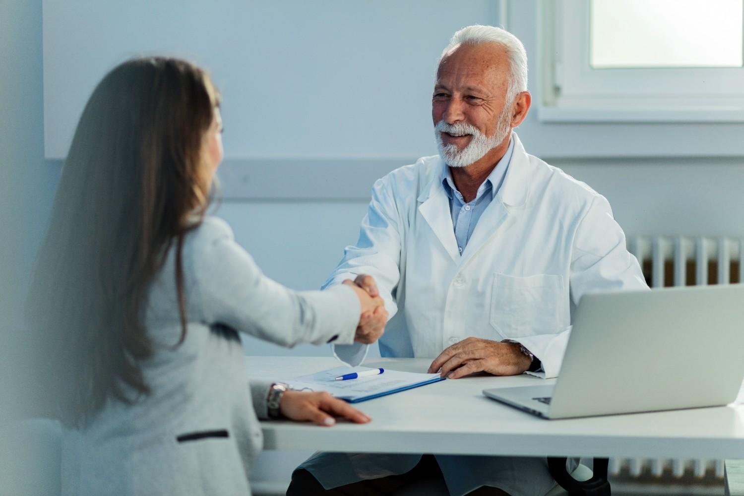 Doctor shaking hands with a client to discuss outsourcing administrative tasks in healthcare