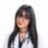 Portrait of a female doctor in a white coat with a stethoscope and purple glasses, looking at the camera with a soft smile.